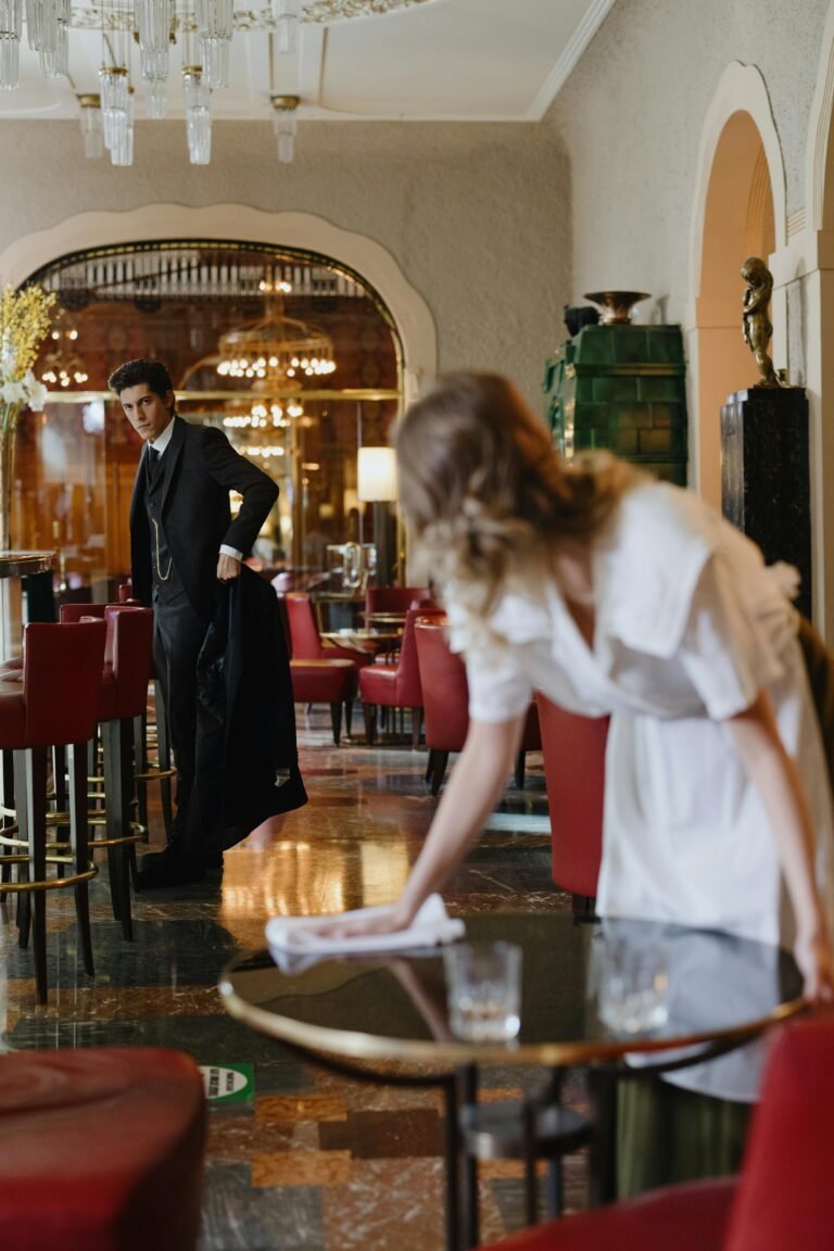 An elegant dining room with attentive waitstaff, red chairs, and sophisticated decor.
